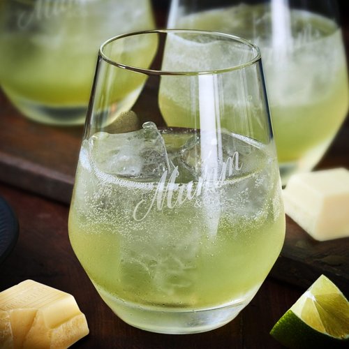 Ein elegantes Glas mit einem sprudelnden, hellgrünen Getränk, gefüllt mit Eiswürfeln und dekoriert mit einer Limettenscheibe.