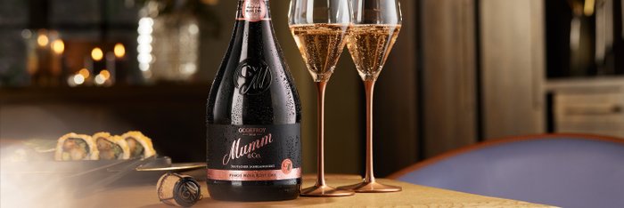 Eine Flasche Godefroy Mumm Sekt steht auf einem Tisch, umgeben von zwei eleganten Gläsern und köstlichem Sushi.