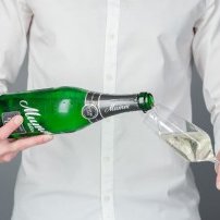 Der Moment des Einschenkens: Ein Mann gießt sprudelnde Flüssigkeit aus einer Flasche in ein Glas, das bereit ist, gefüllt zu werden.