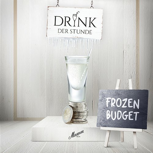 Ein elegantes Glas mit einem klaren Getränk steht auf einem Stapel Münzen, umgeben von einer hellen, minimalistischen Kulisse.