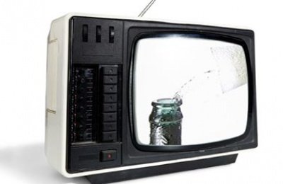 Auf dem Bildschirm eines alten Fernsehers wird Wasser in eine Dose gegossen, was eine nostalgische Atmosphäre erzeugt.