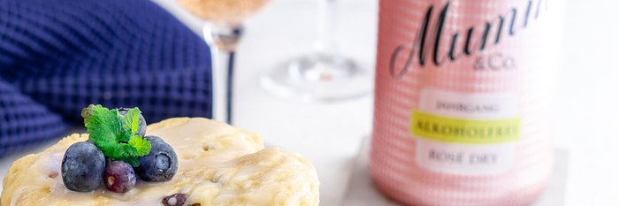 Ein köstlicher Kuchen mit Blaubeeren und frischer Minze, serviert neben einem Glas alkoholfreiem Rosé-Sekt.