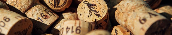 Nahaufnahme von Korken, die in unterschiedlichen Positionen angeordnet sind, einige mit handschriftlichen Notizen und Zahlen.