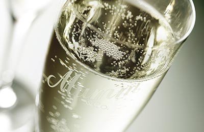 Ein elegantes Sektglas mit sprudelndem Getränk, das in sanftem Licht funkelt und eine festliche Atmosphäre vermittelt.