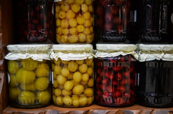Eine Reihe von Einmachgläsern mit verschiedenen Früchten, darunter gelbe und grüne Früchte, die appetitlich aussehen.