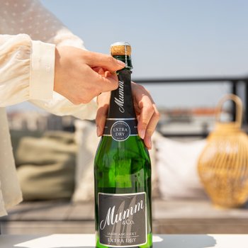 Die Person entfernt den Drahtverschluss von einer Flasche Mumm Extra Dry, um den Sekt zu genießen.