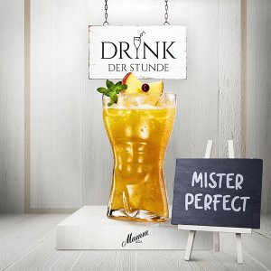 Ein erfrischendes Getränk in einem hohen Glas, garniert mit Minze und Früchten, steht vor einem Schild mit der Aufschrift 'Mister Perfect'.