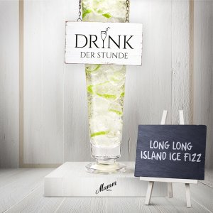 Ein hoher Cocktailglas gefüllt mit Eis und Limettenscheiben, beschriftet mit 'Drink der Stunde'.