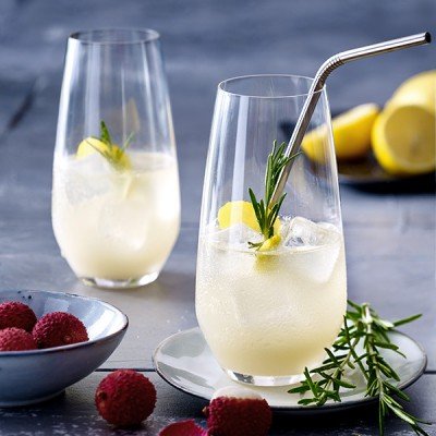 Zwei elegante Gläser mit einem erfrischenden Getränk, garniert mit Zitrone und Rosmarin, stehen auf einem Tisch.