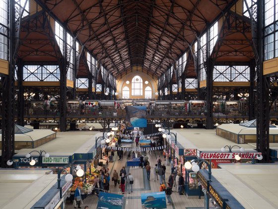 Stände mit frischen Lebensmitteln und Souvenirs ziehen Menschen an, während das Licht durch die hohen Fenster strömt.