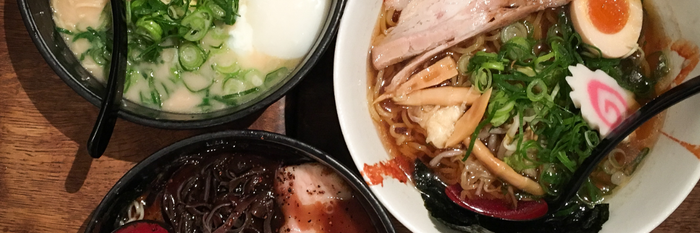 Ein herzhaftes Ramen-Gericht mit zarten Fleischstücken, einem Ei und frischen Zutaten, serviert auf einem Holztisch.
