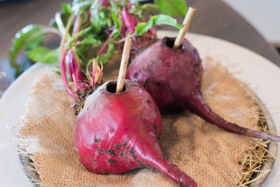 Die Rüben sind kunstvoll angerichtet, mit Holzstäbchen in der Mitte, umgeben von frischen, grünen Blättern.