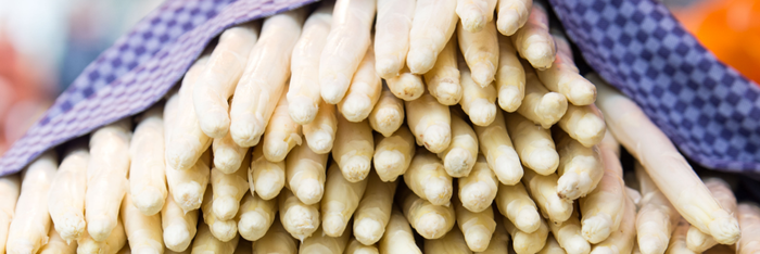 Ein großer Haufen frischer, weißer Spargel, sorgfältig in einem karierten Tuch eingewickelt, strahlt Frische und Qualität aus.