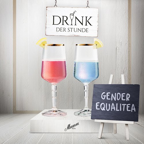 Zwei elegante Gläser mit pinkem und blauem Getränk stehen vor einem Schild mit der Aufschrift 'DRINK DER STUNDE'.
