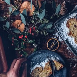 Ein eleganter Tisch mit einem Flasche Sekt, frischem Stollen und dekorativen Pflanzen, die eine festliche Atmosphäre schaffen.