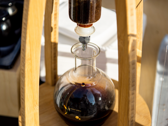 Ein modernes Kaffeegerät aus Holz und Glas, das aromatischen Kaffee in eine transparente Karaffe leitet.