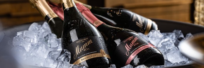 Die Flaschen Sekt sind mit Wassertropfen bedeckt und ruhen auf einer Schicht aus klarem Eis in einer eleganten Schüssel.