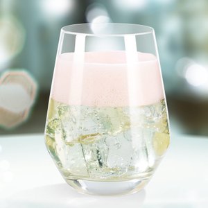 Das Glas zeigt eine schaumige, rosafarbene Oberseite und klare Blasen, die im Getränk aufsteigen.