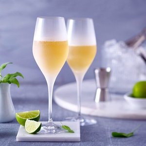 Ein stilvolles Arrangement mit zwei Gläsern, gefüllt mit einem hellen Getränk, und frischen Limetten auf einem Marmoruntergrund.