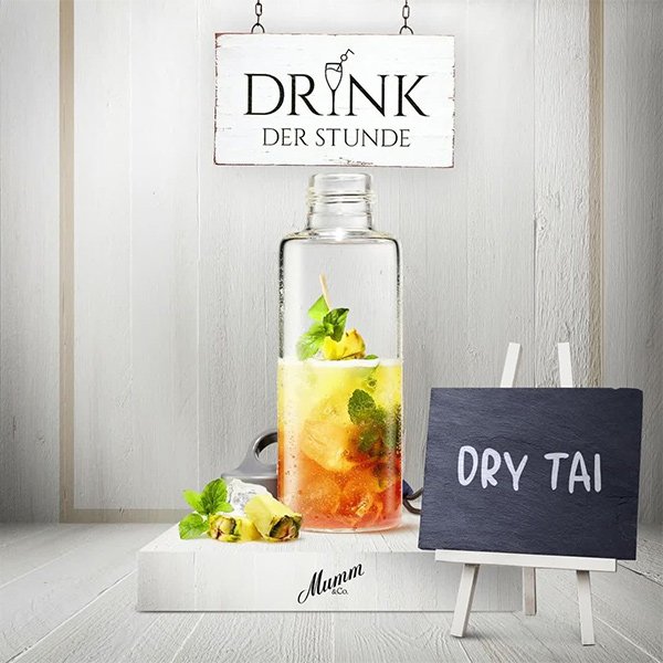 Ein eleganter Glasbehälter mit einem bunten Getränk, garniert mit frischer Minze und einer Ananasscheibe, steht auf einem weißen Tisch.