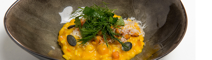 Das Risotto, leuchtend gelb und reichhaltig, wird mit frischen Kräutern und geriebenem Käse dekoriert, was es appetitlich macht.