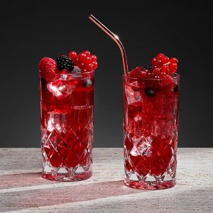Zwei glitzernde Gläser mit roten Cocktails, gefüllt mit Eis und frischen Beeren, stehen auf einer hellen Oberfläche.