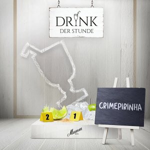 Ein stilvolles Schild mit der Aufschrift 'DRINK DER STUNDE' hängt über einer kreativen Cocktail-Darstellung aus Eis und Limetten.