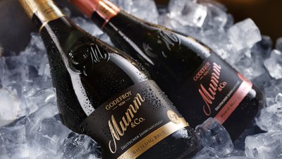 Zwei Flaschen Sekt von Godefroy von Mumm & Co. liegen auf Eis, umgeben von glitzernden Eiskristallen.