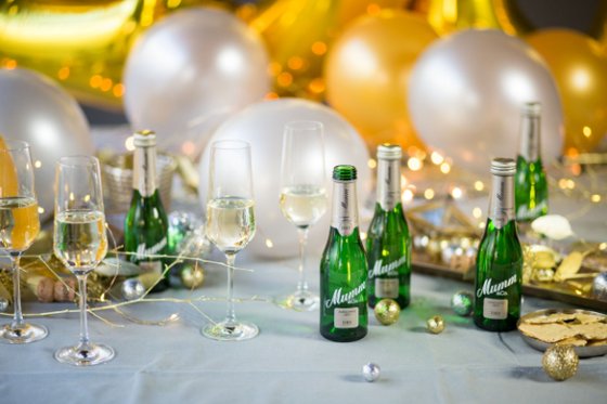 Ein festlich gedeckter Tisch mit Sektgläsern, kleinen Flaschen und bunten Luftballons, die eine fröhliche Atmosphäre schaffen.